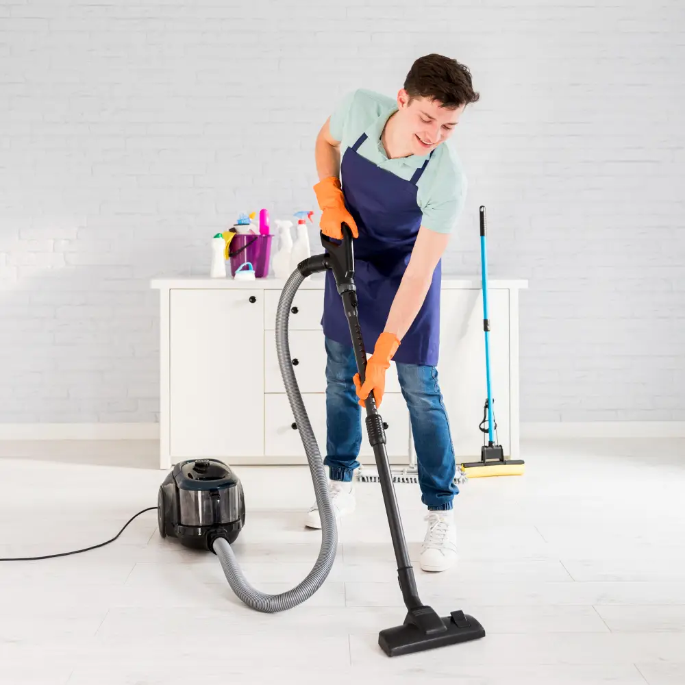 Professional cleaner vacuuming a bright home while smiling