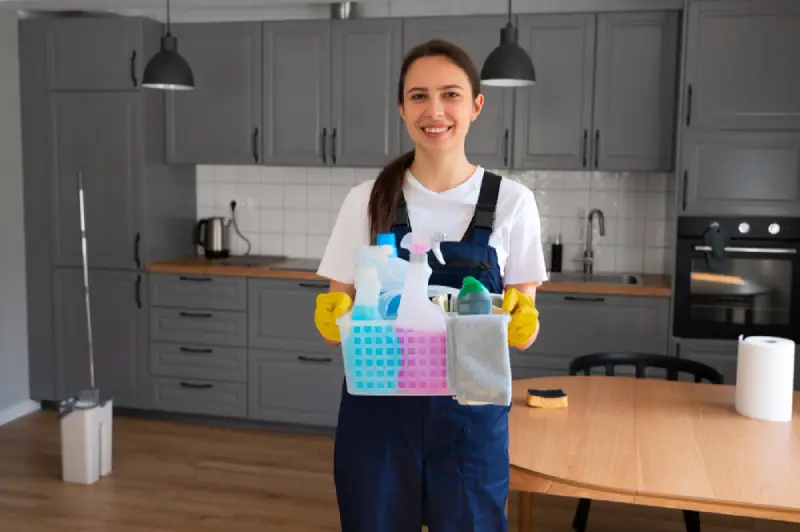 Professional domestic cleaner with cleaning supplies in a London kitchen